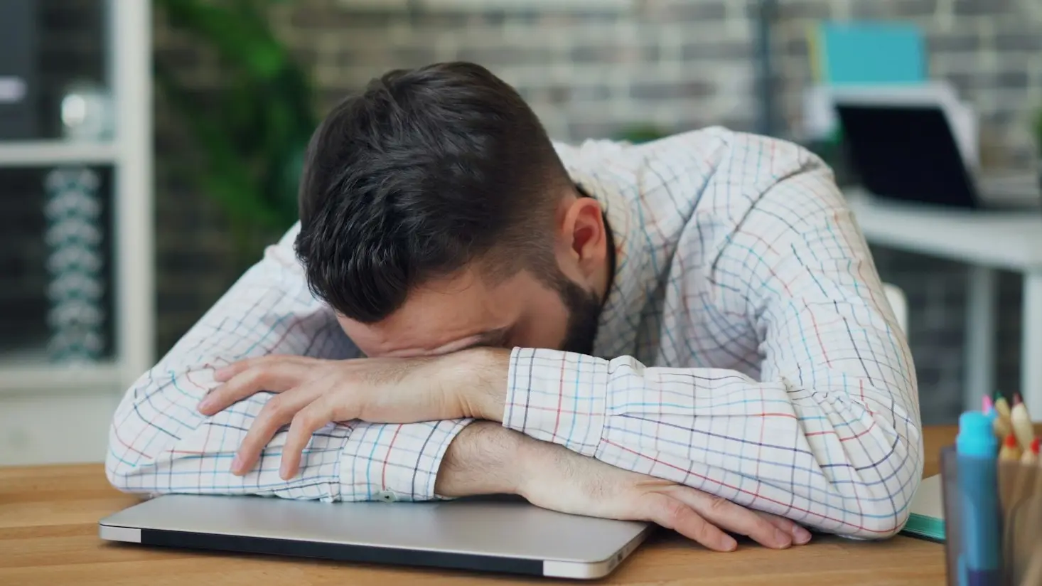 a man sitting at a desk with his head in his hands