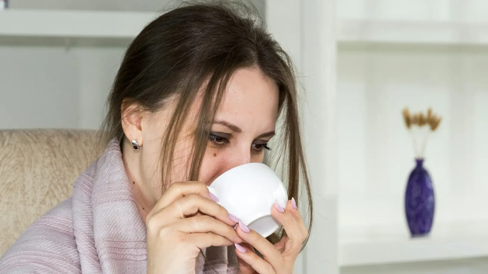 a woman sitting in a chair drinking from a cup